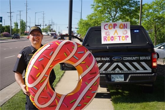 Man with blow-up donut in front of truck with sign that says Cop on a Rooftop
