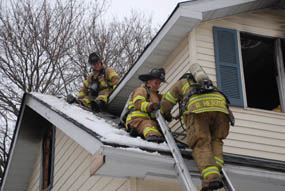 3 firefighters on a roof.